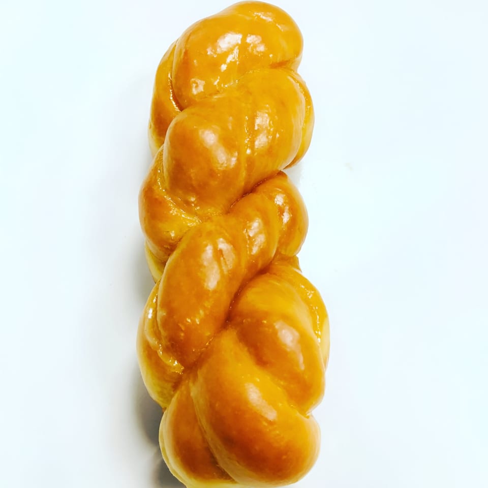 A glazed, golden-brown twisted donut from Donut Taco Palace on a white background.